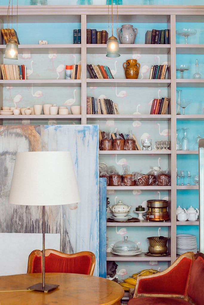 7 Ide Wallpaper Tak Biasa yang Membuat Ruang Terlihat Lebih Dramatis dan Eksklusif 3 Charming vintage room with bookshelves, decor, and warm lighting.