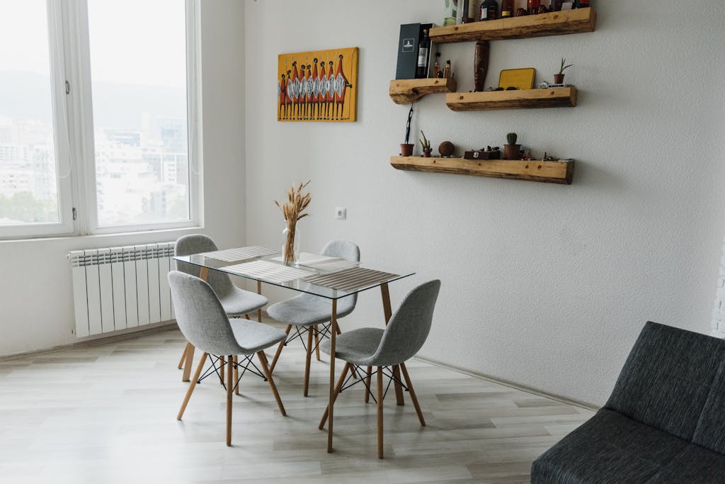 Awas Rusak! Ini di 5 Tempat Menggantung Lukisan yang Harus Kamu Hindari 3 Elegant dining area with glass table, chairs, and wall art.