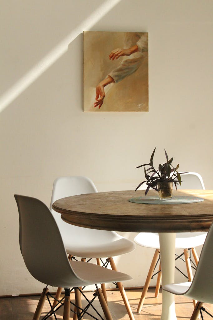 5 Tren Ruang Makan 2026 yang Akan Mengubah Tampilan Rumahmu 4 Sunlit minimalist dining room with round table, chairs, and painting.