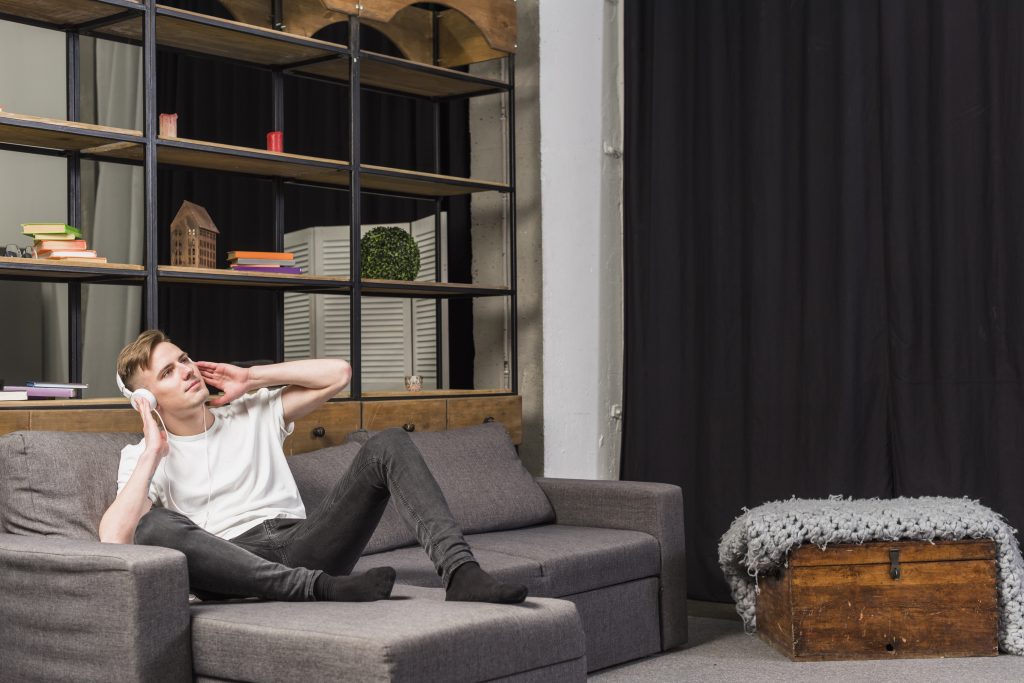 Investasi Interior: Ini Bagian Rumah yang Layak Dibayar Mahal 7 young man relaxing sofa listening music headphone home