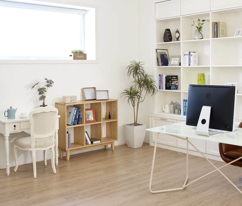 Contemporary home office setup with natural light, featuring modern decor, desk, computer, and bookshelves.