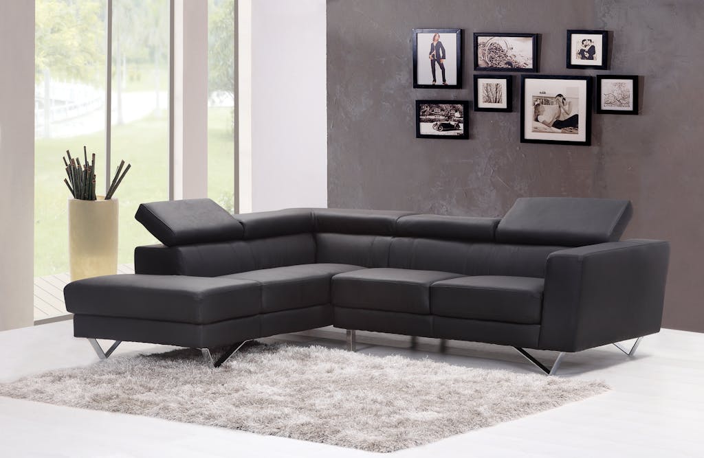 Mau Memilih Karpet? Ini 5 Hal Ini Wajib Kamu Tahu Agar Tidak Menyesal 3 Contemporary living room featuring a sleek black sectional sofa and chic wall art.