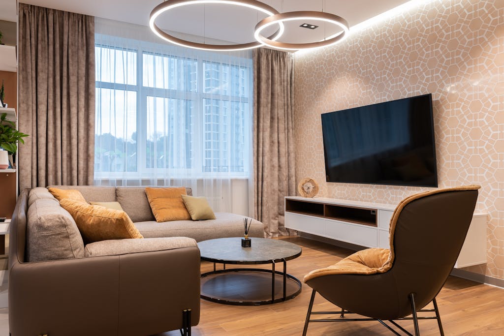 Wallpaper Ruangan Kecil: 7 Cara Wallpaper Bisa Membuat Kamar Terlihat Lebih Luas & Lapang 3 Cozy living room with contemporary furnishings, stylish decor, and a large TV, ideal for relaxation.