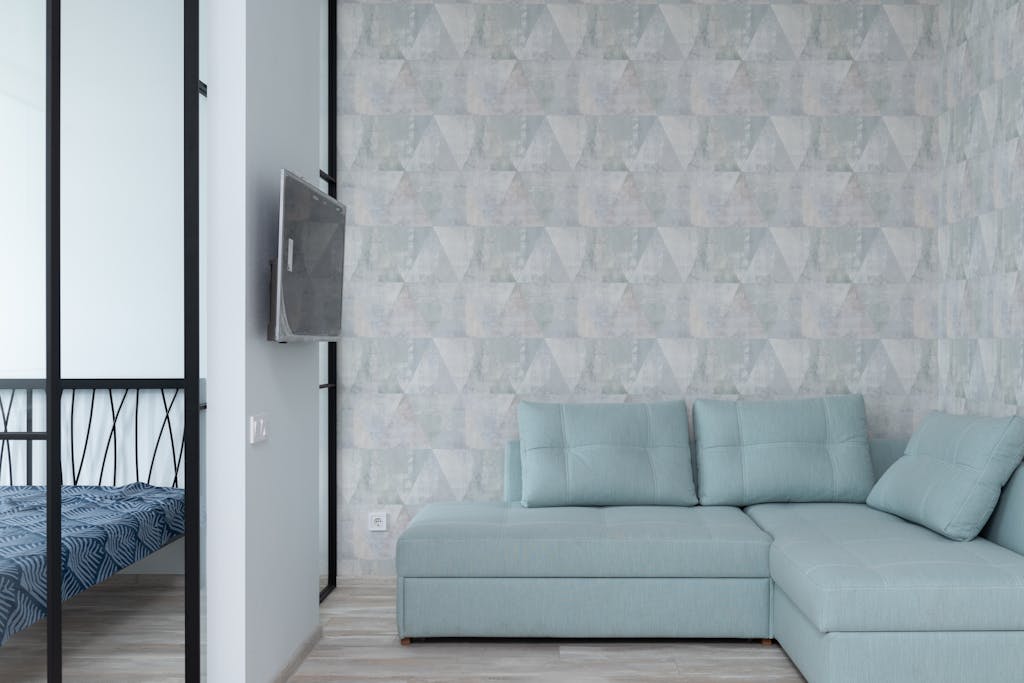 Wallpaper Ruangan Kecil: 7 Cara Wallpaper Bisa Membuat Kamar Terlihat Lebih Luas & Lapang 5 Cozy modern living room with pastel-colored sofa and geometric wallpaper.