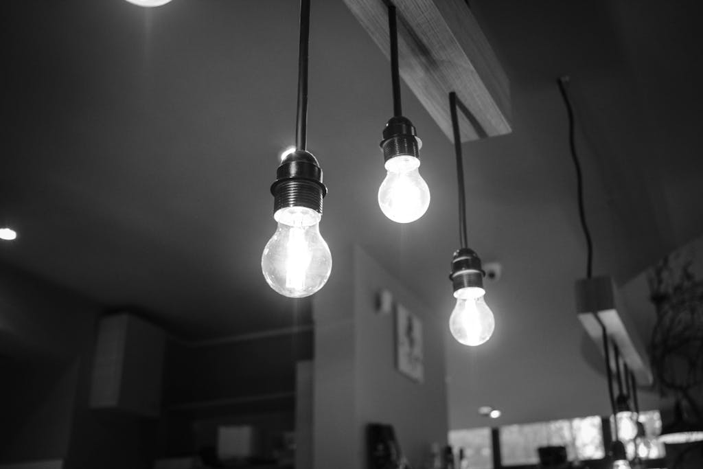 Elegant black and white photo of illuminated hanging bulbs indoors.