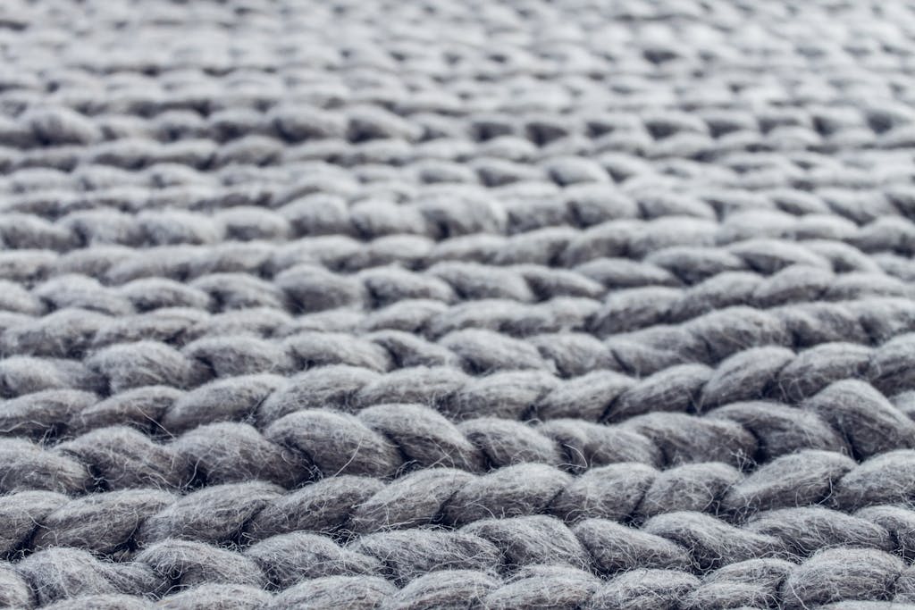 Mau Memilih Karpet? Ini 5 Hal Ini Wajib Kamu Tahu Agar Tidak Menyesal 2 Macro photograph showing the intricate details of grey knitted wool fibers.