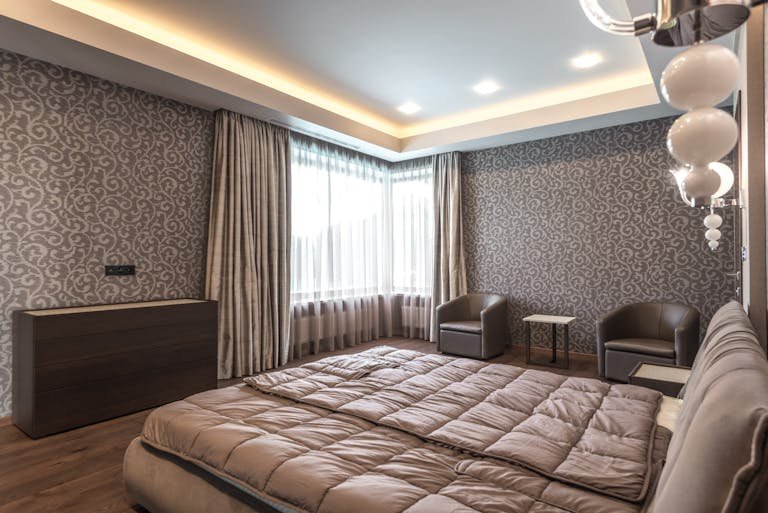 Spacious modern bedroom featuring elegant decor and luxurious furnishings.
