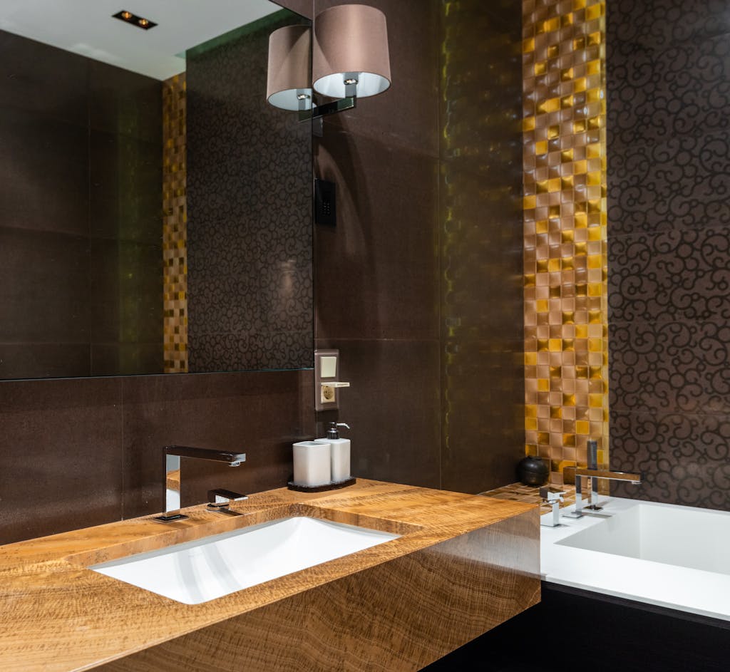 Stylish modern bathroom featuring a wooden sink, elegant bathtub, and intricate wallpaper design.