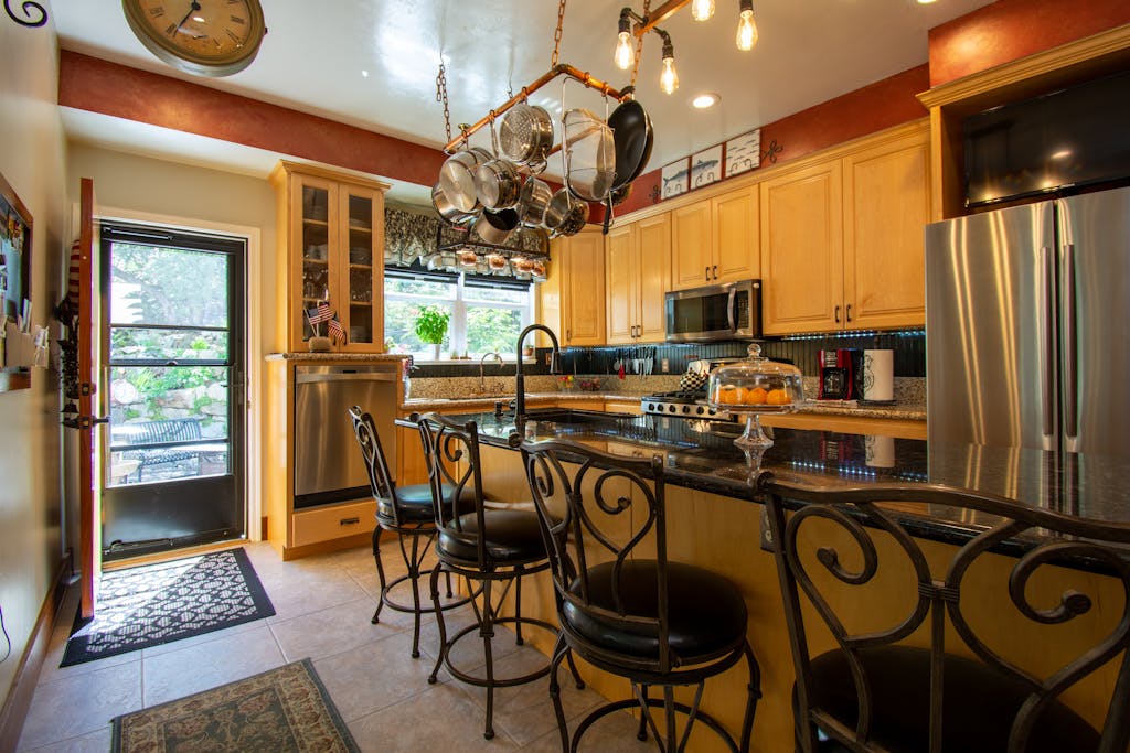 A stylish kitchen featuring granite countertops, bar stools, and stainless steel appliances.