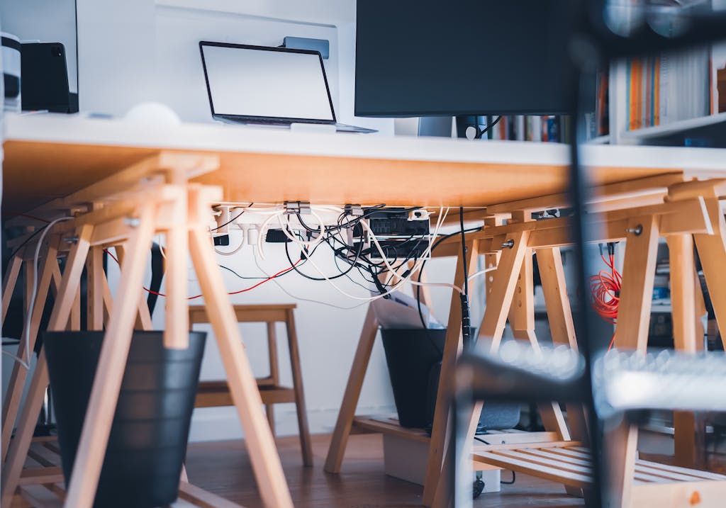 A stylish workspace with visible cables, laptop and monitor, highlighting modern technology's complexity.