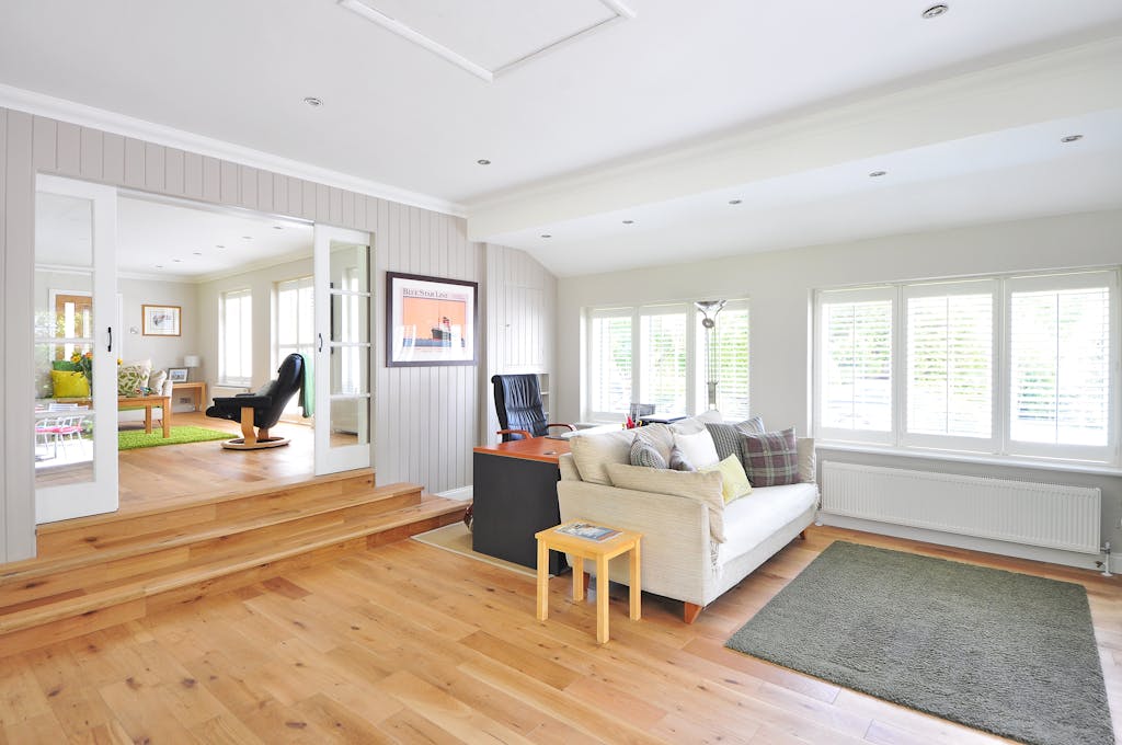 6 Pilihan Flooring Rumah yang Membuat Ruangan Terlihat Mewah 7 Spacious and bright modern living room with wooden floors and stylish furniture.